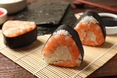 Photo of Tasty onigiri (Japanese rice balls) with shrimps on wooden table, closeup