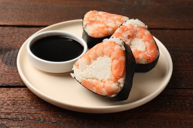 Photo of Tasty onigiri (Japanese rice balls) with shrimps and soy sauce on wooden table, closeup