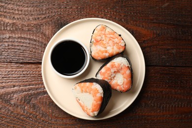 Photo of Tasty onigiri (Japanese rice balls) with shrimps and soy sauce on wooden table, top view