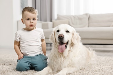 Photo of Little boy with cute dog on carpet at home