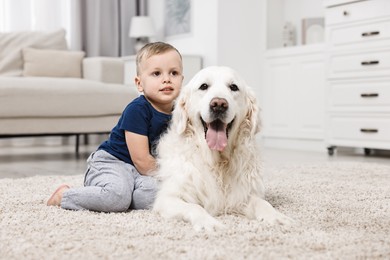 Little boy with cute dog on carpet at home