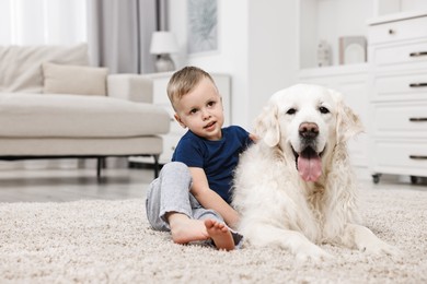 Little boy with cute dog on carpet at home