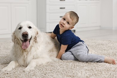 Little boy with cute dog on carpet at home