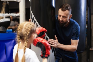 Boxing coach training girl in sport center