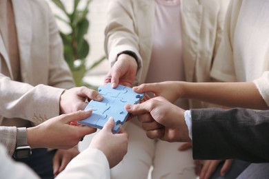 Photo of Unity concept. People putting puzzle pieces together indoors, closeup