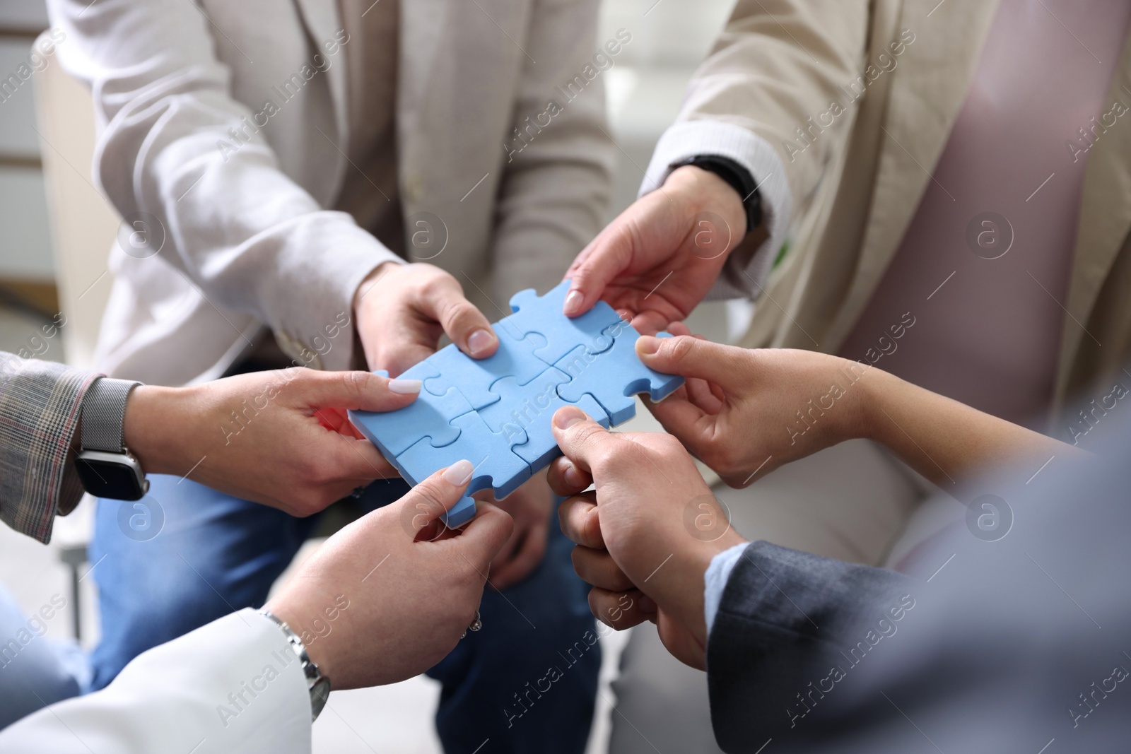 Photo of Unity concept. People putting puzzle pieces together indoors, closeup