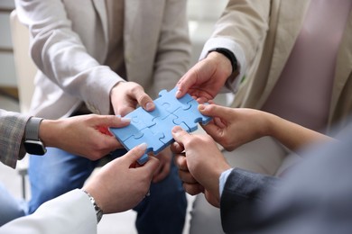 Photo of Unity concept. People putting puzzle pieces together indoors, closeup