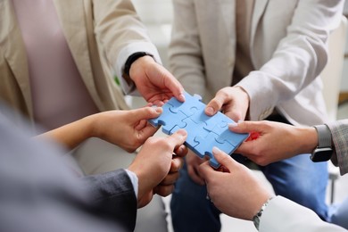 Unity concept. People putting puzzle pieces together indoors, closeup