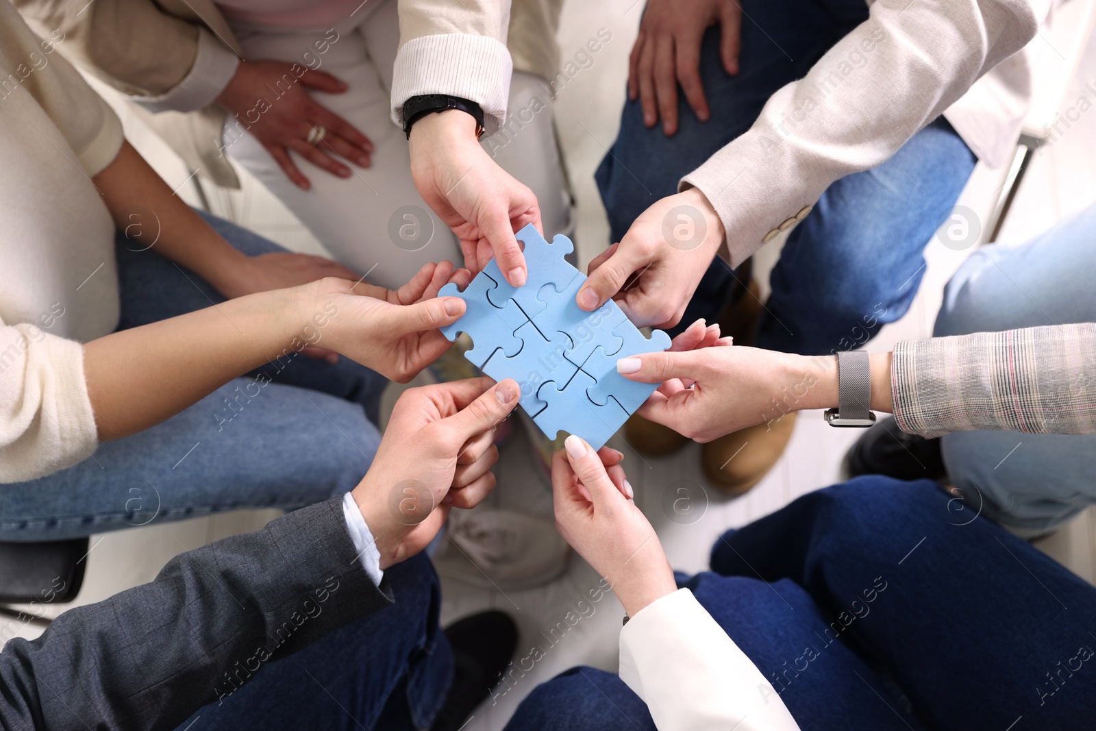 Photo of Unity concept. People putting puzzle pieces together indoors, top view