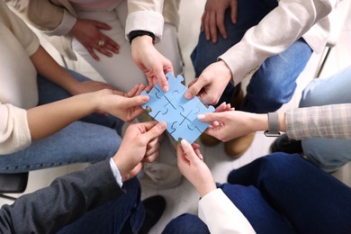 Unity concept. People putting puzzle pieces together indoors, top view