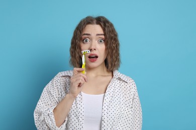 Excited woman shaving her mustache with razor on light blue background