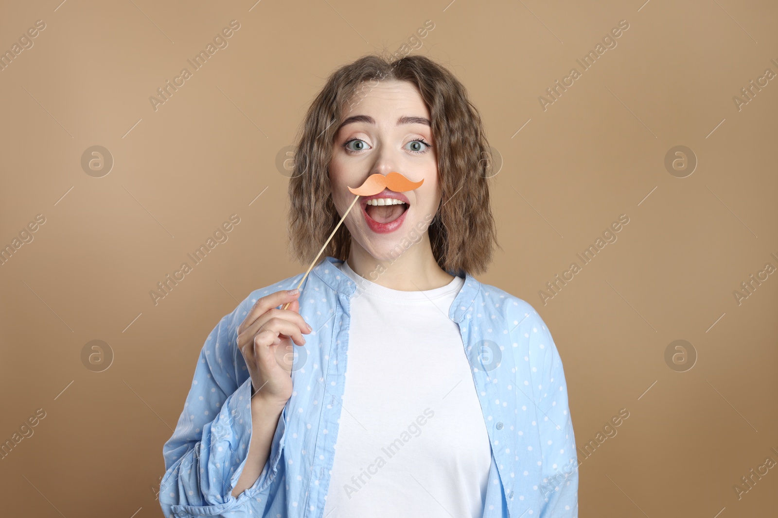 Photo of Funny woman with fake paper mustache on beige background