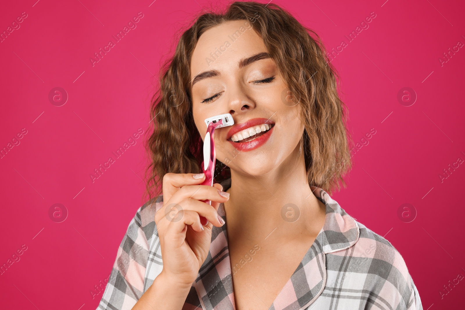 Photo of Happy woman shaving her mustache with razor on pink background