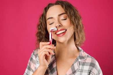 Photo of Happy woman shaving her mustache with razor on pink background