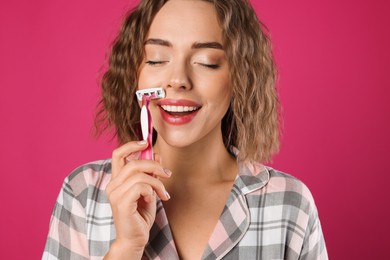 Photo of Happy woman shaving her mustache with razor on pink background