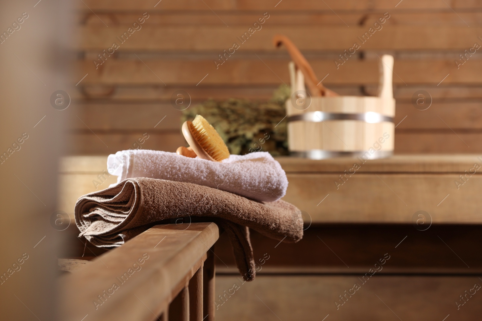 Photo of Massaging brush, stack of towels and other supplies in sauna, selective focus