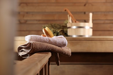 Massaging brush, stack of towels and other supplies in sauna, selective focus