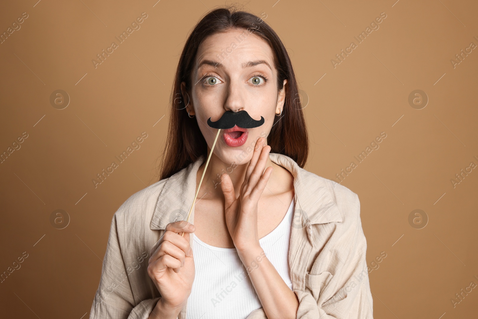 Photo of Surprised woman with fake paper mustache on brown background