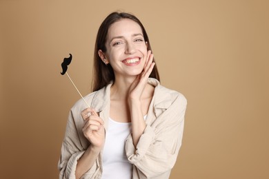 Photo of Happy woman with fake paper mustache on brown background