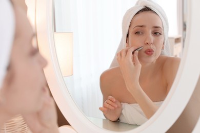 Beautiful woman plucking her mustache with tweezers near mirror at home