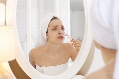 Photo of Beautiful woman shaving her mustache with razor near mirror at home