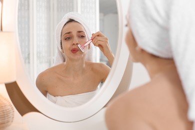 Photo of Beautiful woman shaving her mustache with razor near mirror at home