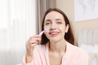 Photo of Happy woman shaving her mustache with razor at home