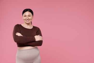 Plus size woman in gym clothes on pink background, space for text