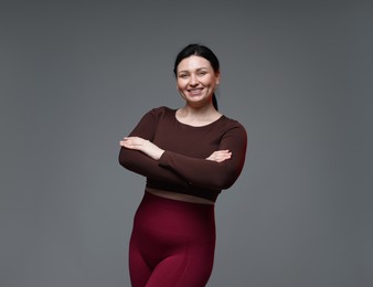 Plus size woman in gym clothes on grey background