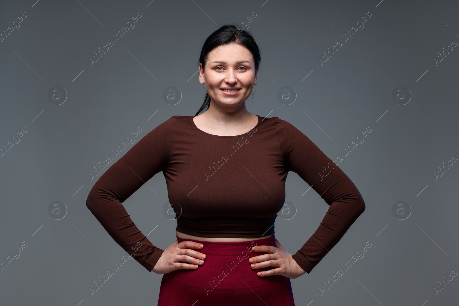 Photo of Plus size woman in gym clothes on grey background