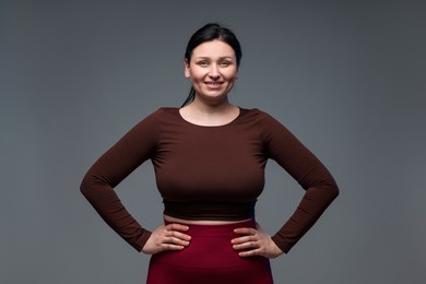 Plus size woman in gym clothes on grey background