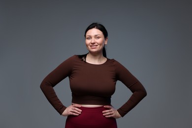 Photo of Plus size woman in gym clothes on grey background