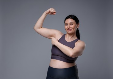 Plus size woman in gym clothes on grey background