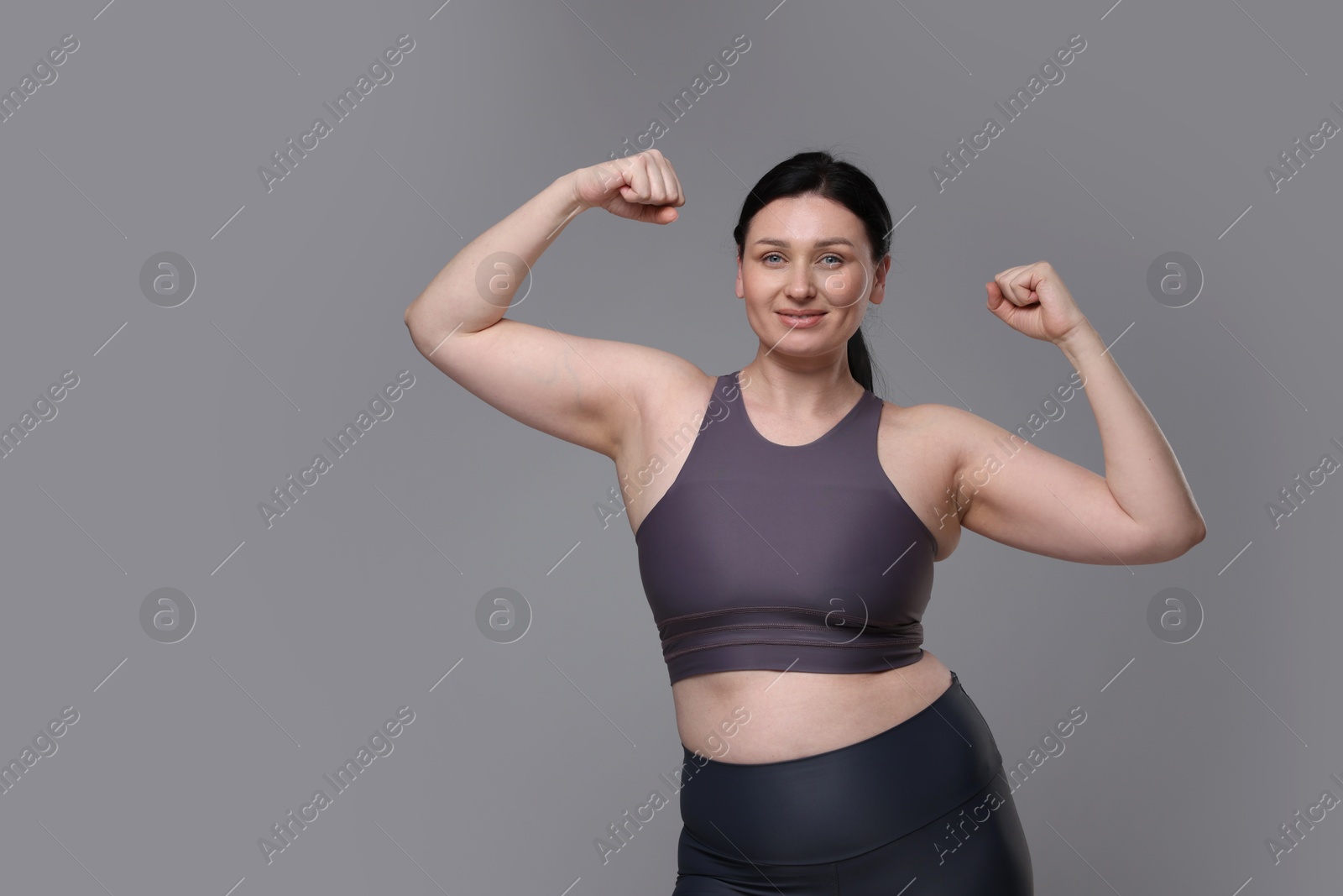 Photo of Plus size woman in gym clothes on grey background, space for text