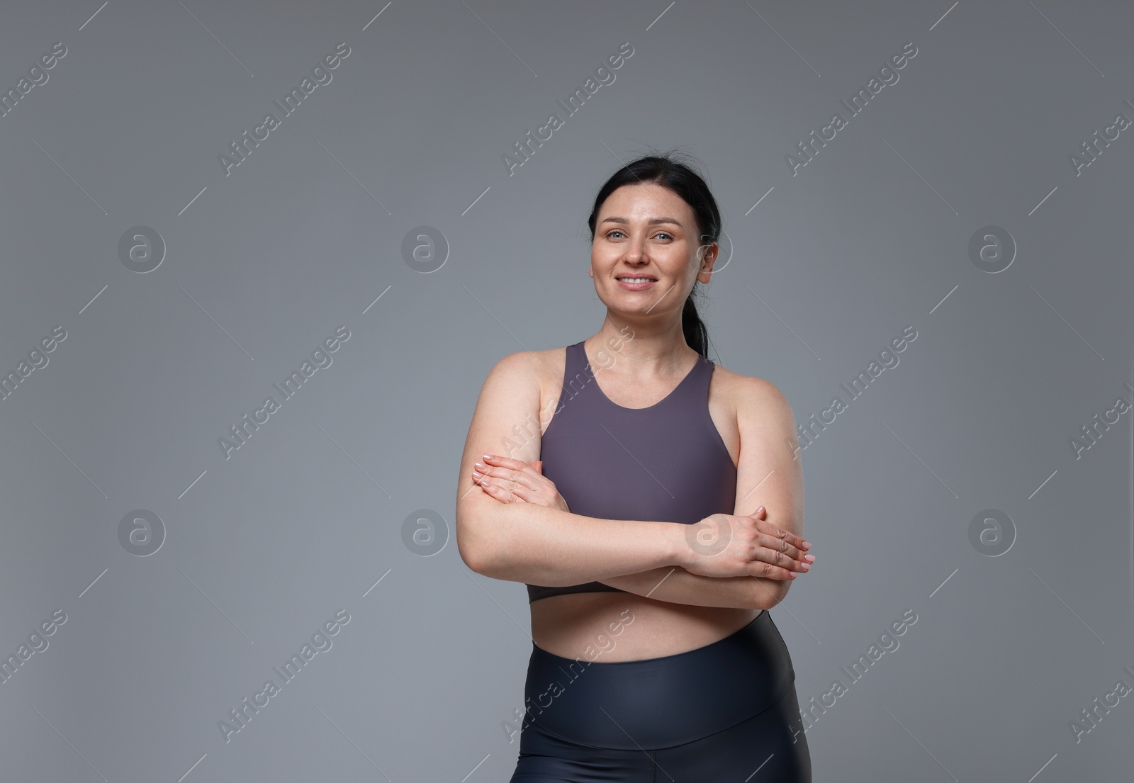 Photo of Plus size woman in gym clothes on grey background, space for text