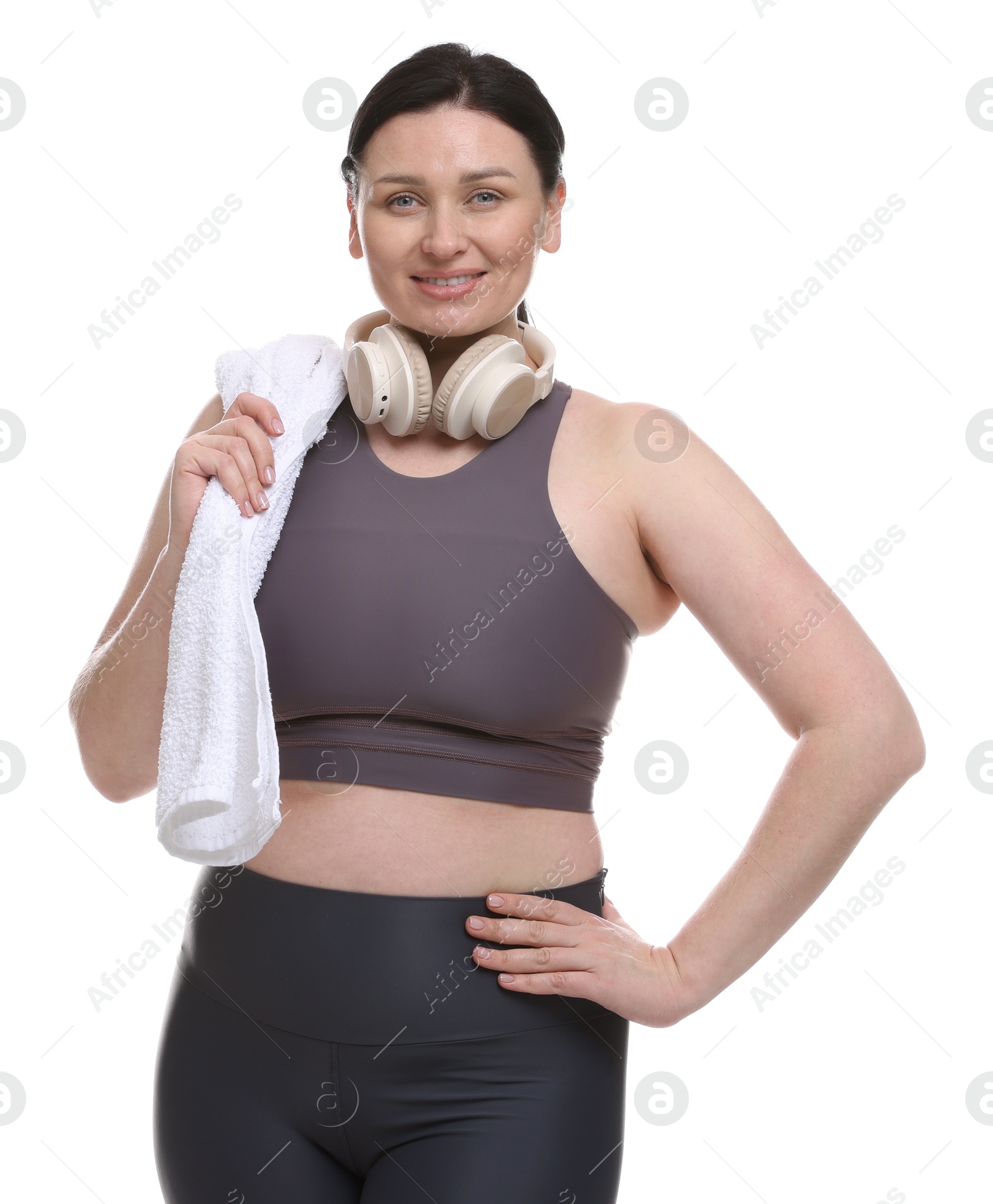 Photo of Plus size woman in gym clothes with headphones and towel on white background