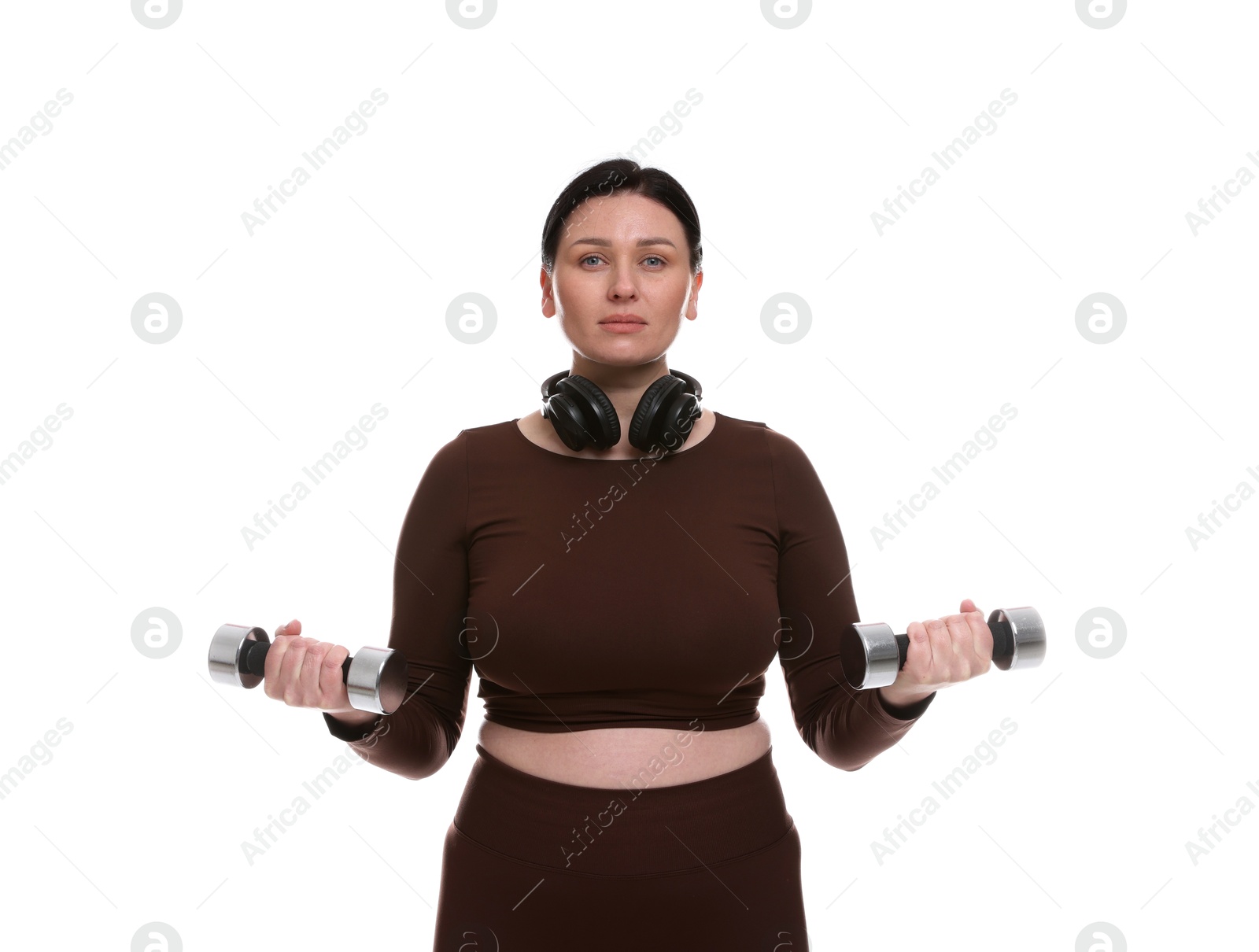 Photo of Plus size woman in gym clothes doing exercise with dumbbells on white background