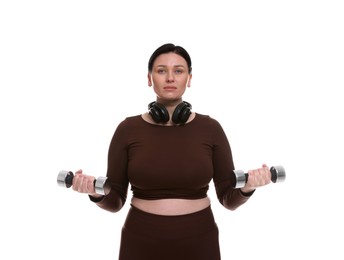 Photo of Plus size woman in gym clothes doing exercise with dumbbells on white background