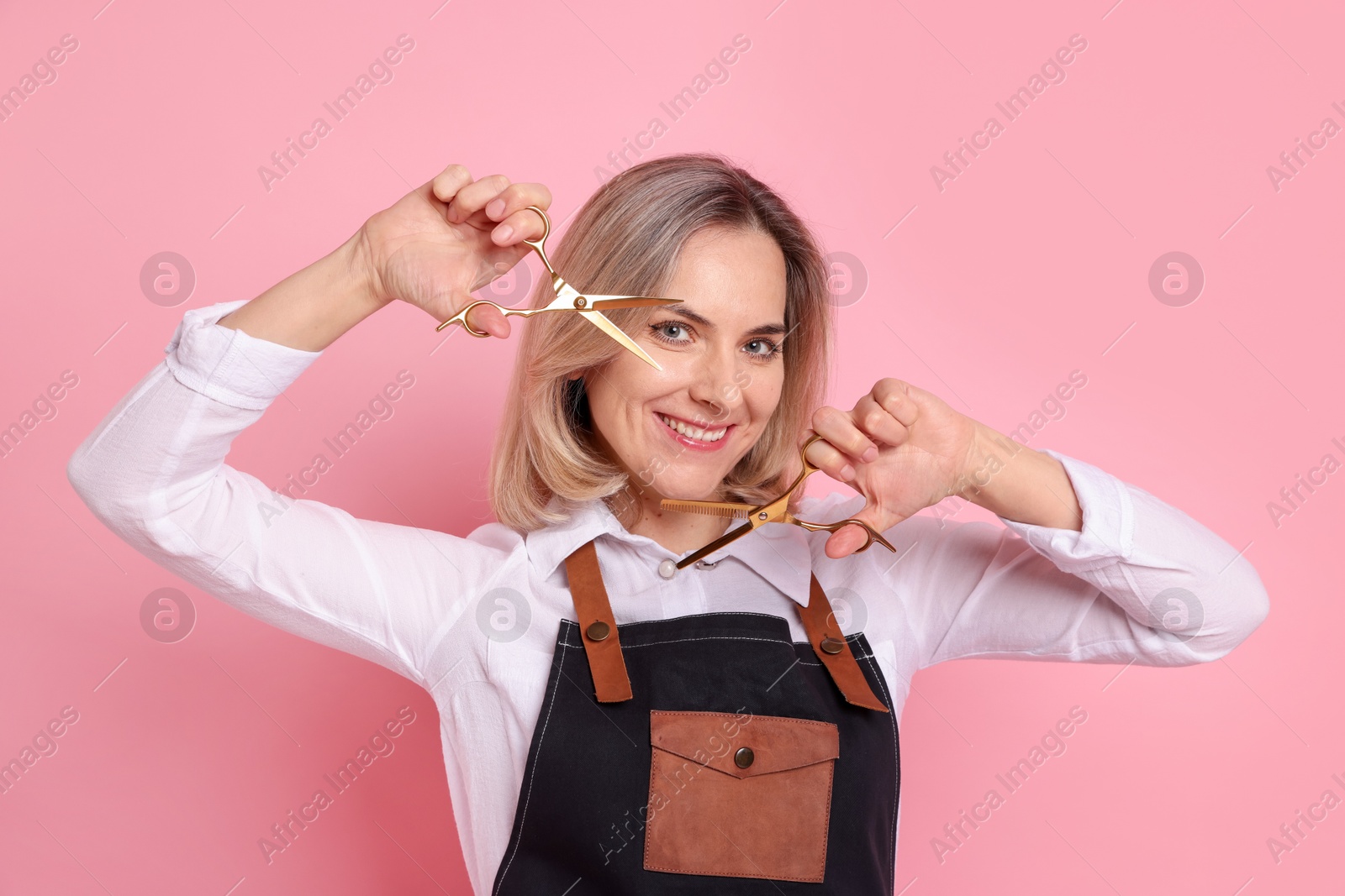 Photo of Smiling hairdresser with scissors on pink background