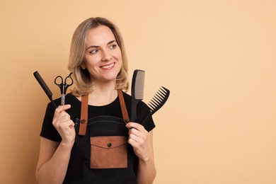 Smiling hairdresser with combs and scissors on beige background, space for text