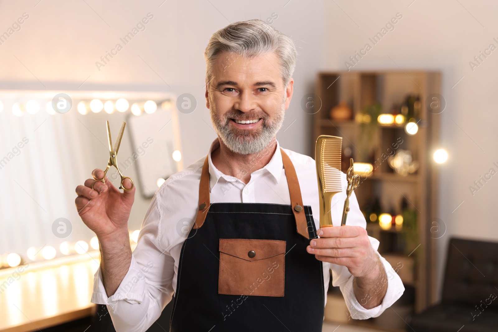 Photo of Smiling hairdresser with scissors and comb in beauty salon