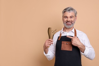 Photo of Smiling hairdresser with scissors and comb on beige background, space for text