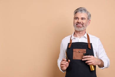 Smiling hairdresser with scissors and spray bottle on beige background, space for text