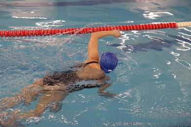 Photo of Woman wearing swimsuit and cap swimming in pool indoors