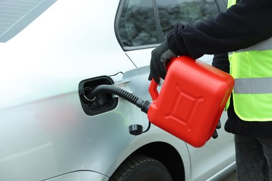 Photo of Man with canister refueling car outdoors, closeup