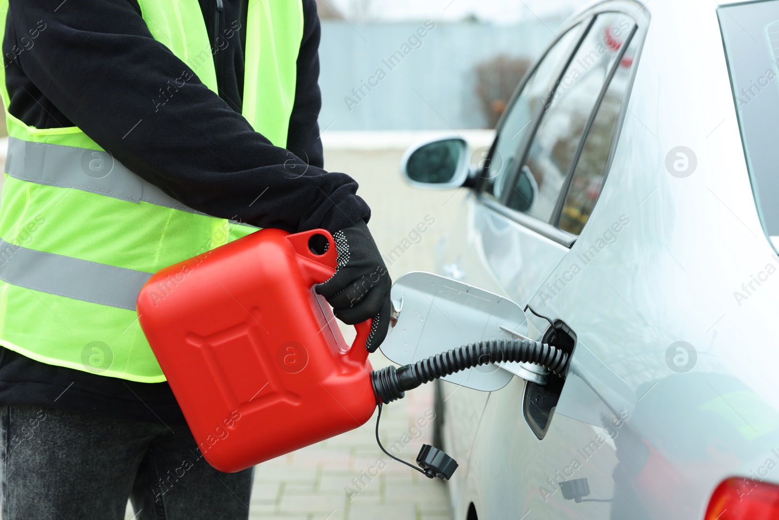 Photo of Man with canister refueling car outdoors, closeup