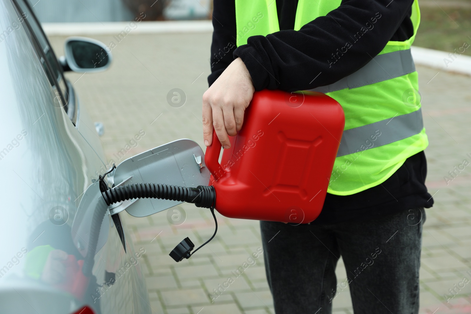 Photo of Man with canister refueling car outdoors, closeup