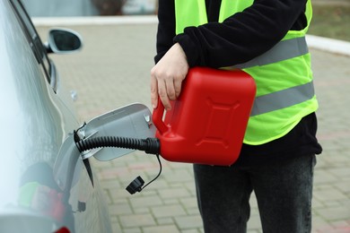 Photo of Man with canister refueling car outdoors, closeup