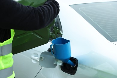 Photo of Man pouring fuel from canister into funnel outdoors, closeup