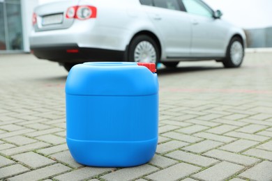 Photo of Light blue plastic canister on pavement outdoors